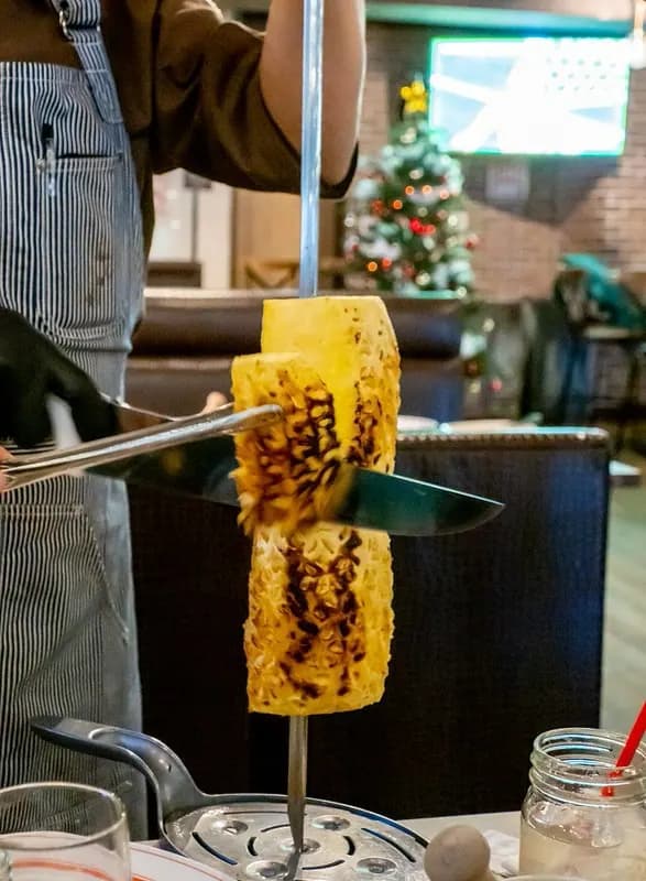 シナモンをまとわせた焼きパイナップルを串から切り分けるところ